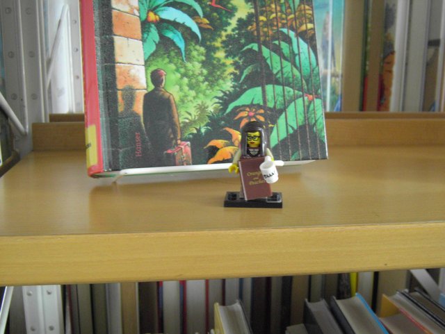 Eine kleine Legofigur steht vor einem Buch.
